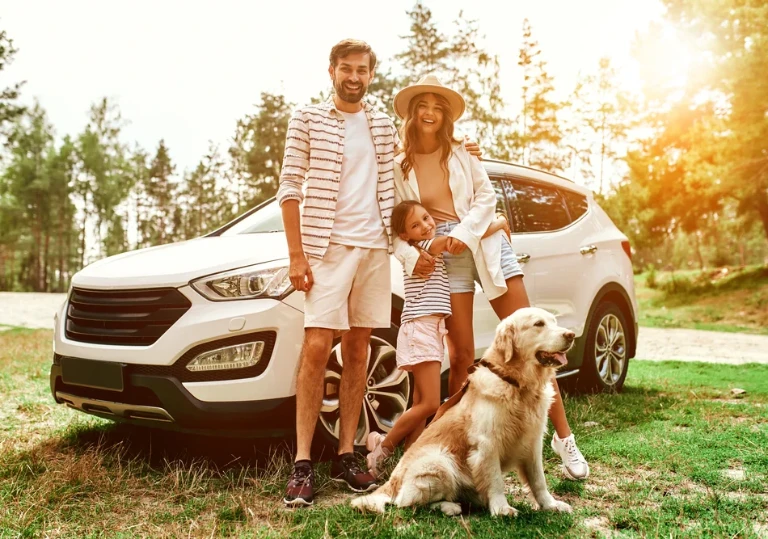 rodzina z&nbsp;psem przed autem